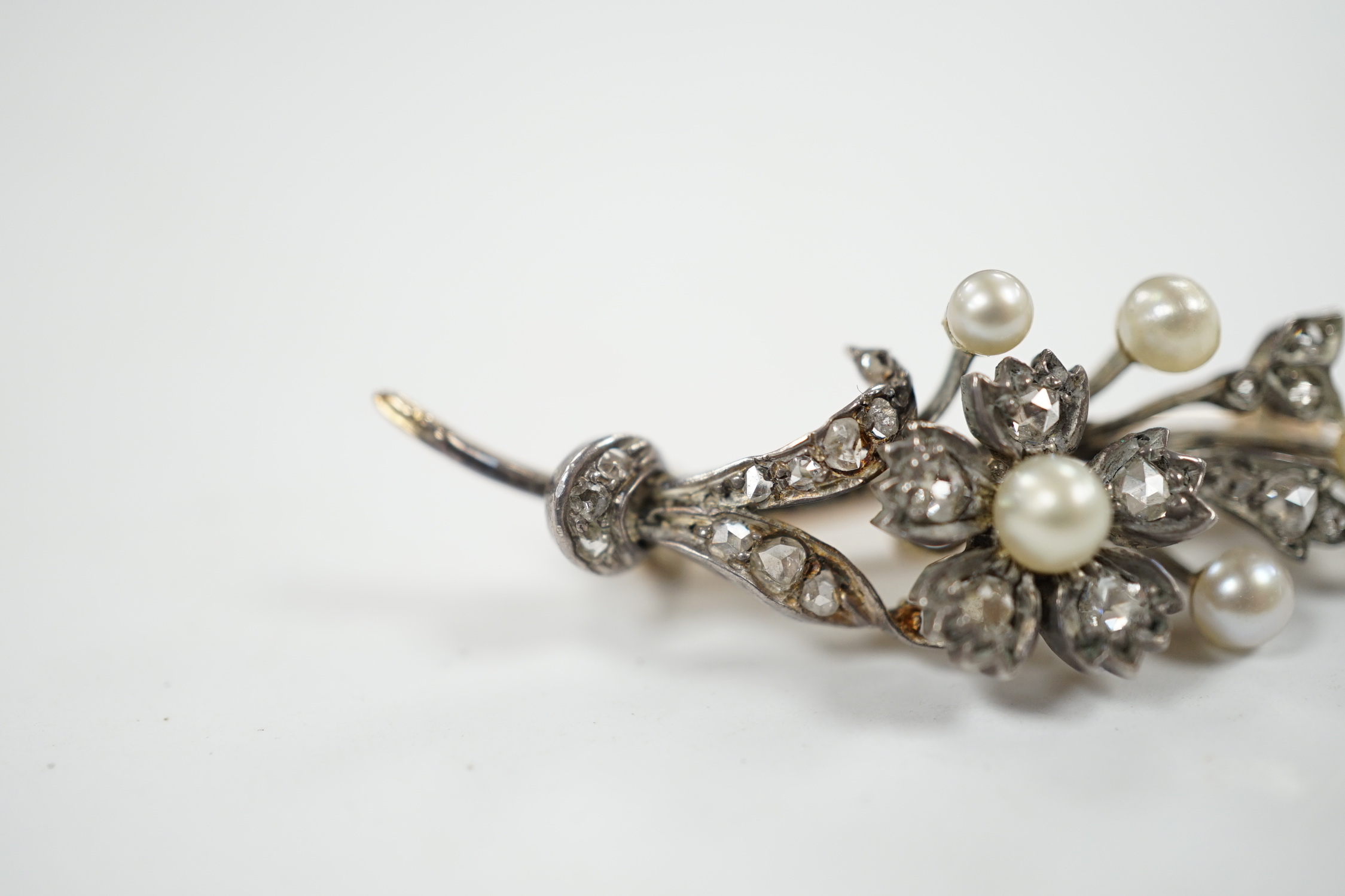 A cased Victorian yellow metal, seed pearl and rose cut diamond set foliate spray brooch, 39mm, gross weight 4.4 grams.